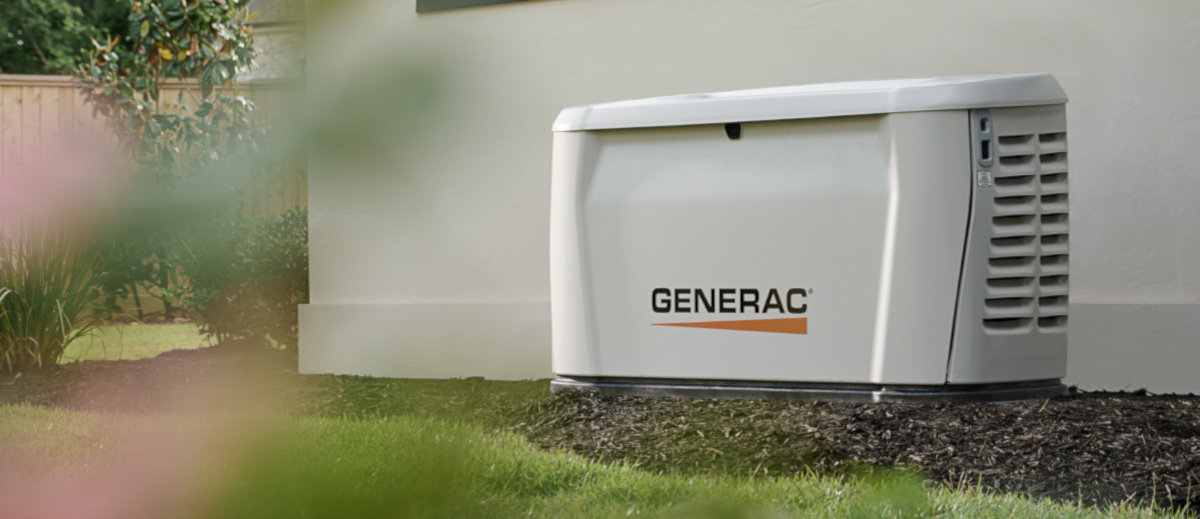 A modern home standby generator installed on the side of a house, quiet and running while the yard is calm
