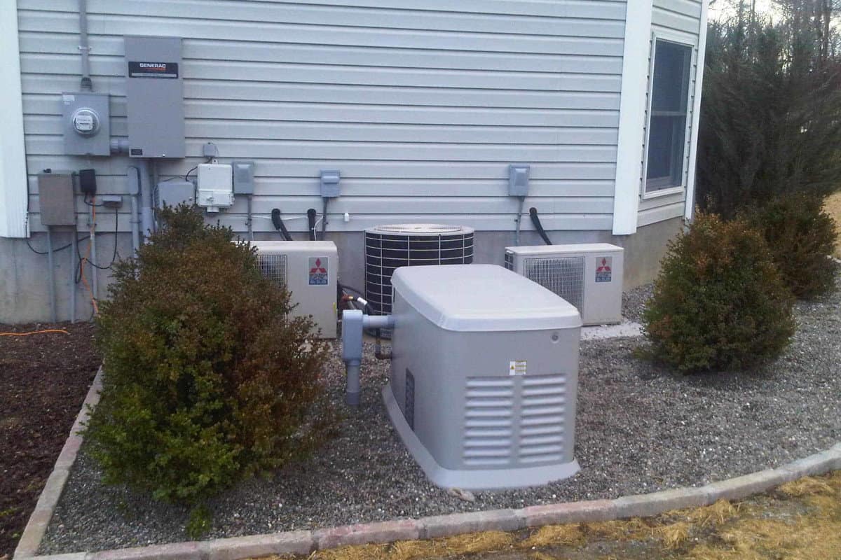 A home standby generator installed beside a house next to the electric meter and automatic transfer switch